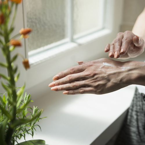 A woman applies lotion to her hand. 